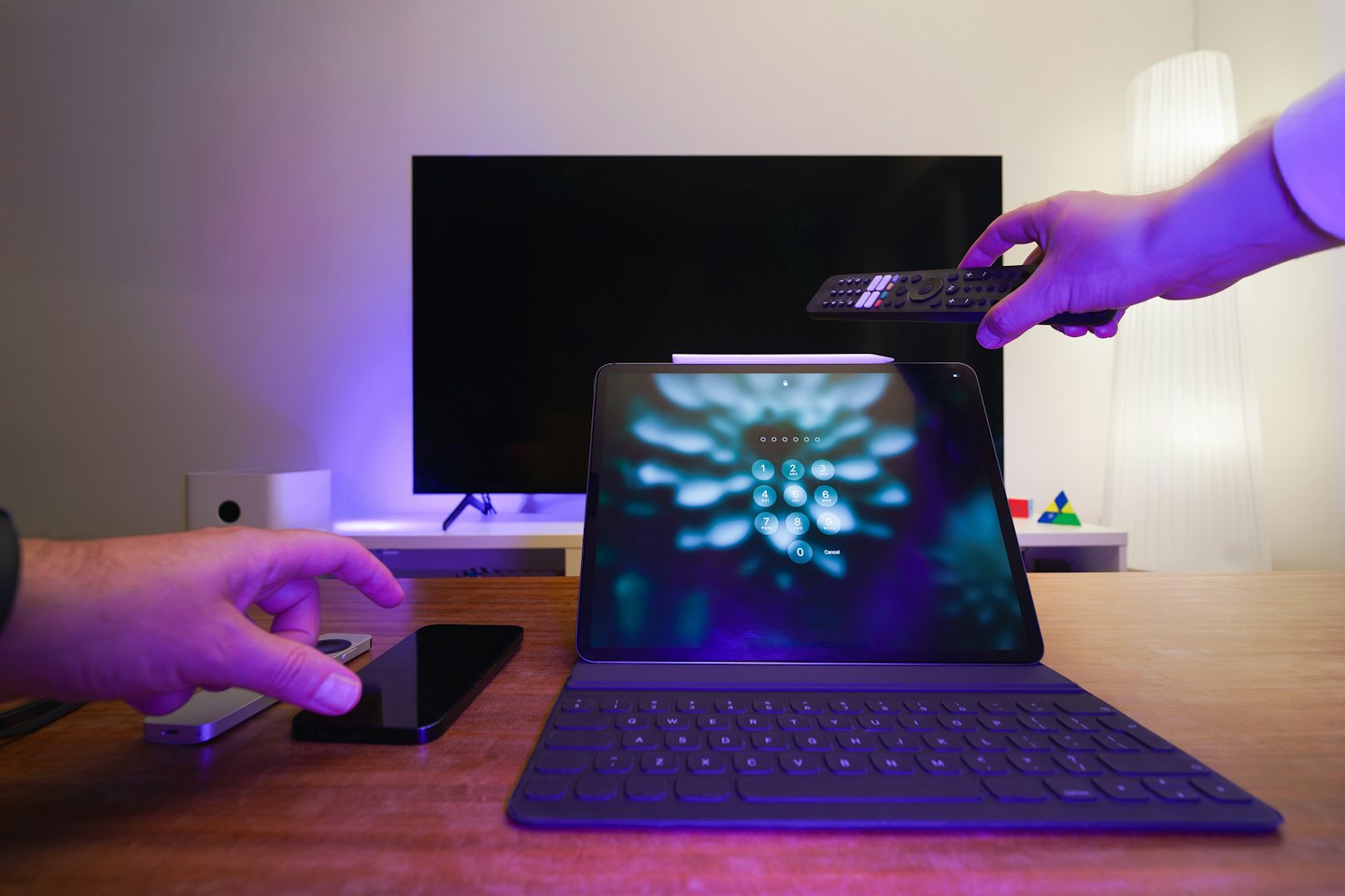 Hands interacting with smart home technology on a desk.